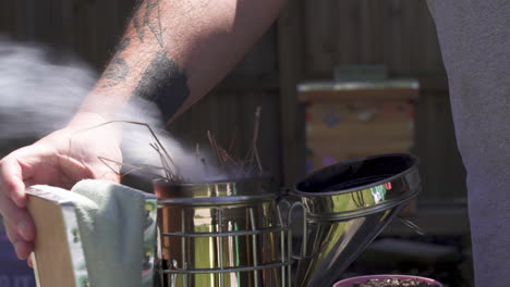 beekeeper using a smoker to calm bees