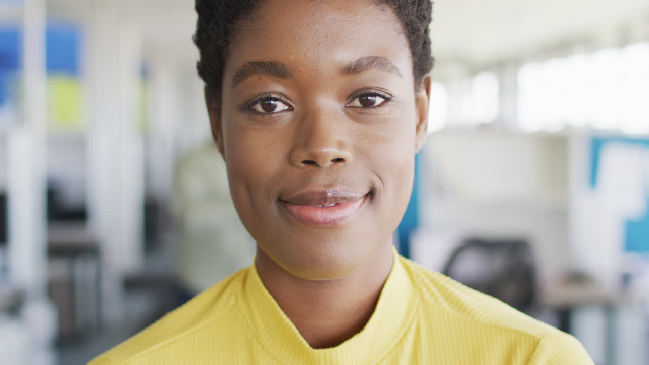 retrato de una mujer de negocios afroamericana mirando a la cámara y sonriendo en la oficina, cámara lenta