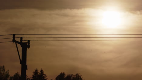 silueta de líneas eléctricas contra el cielo de la hora dorada naranja vívida, telefoto