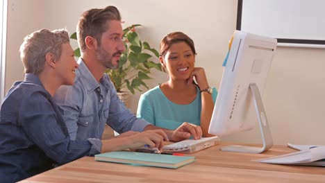 Creative-business-team-using-computer-and-looking-at-camera