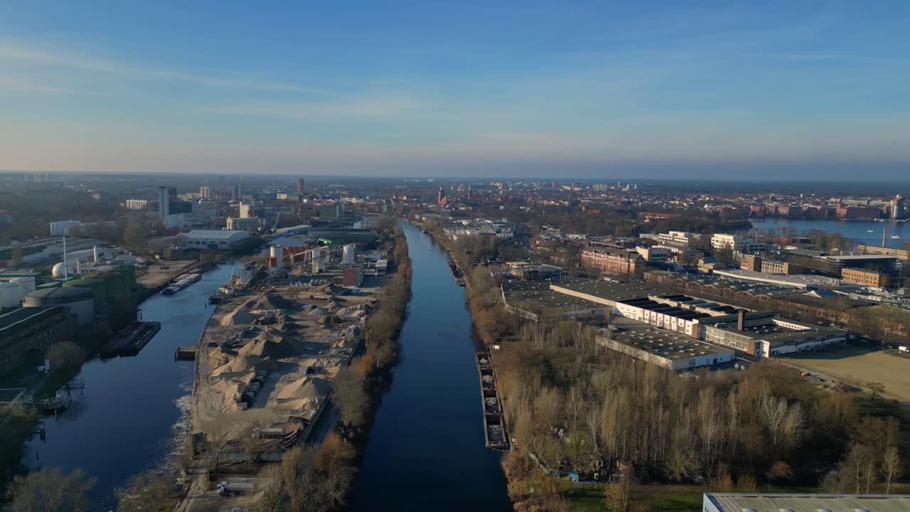 large industrial power plant emitting large amounts of smoke over the city Berlin next to a river on a sunny day. Perfect aerial view flight rotation to right drone