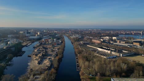 large industrial power plant emitting large amounts of smoke over the city berlin next to a river on a sunny day. perfect aerial view flight rotation to right drone