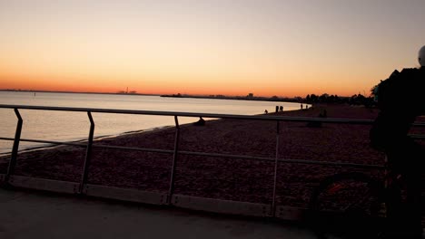 cyclist rides along beach path at sunset