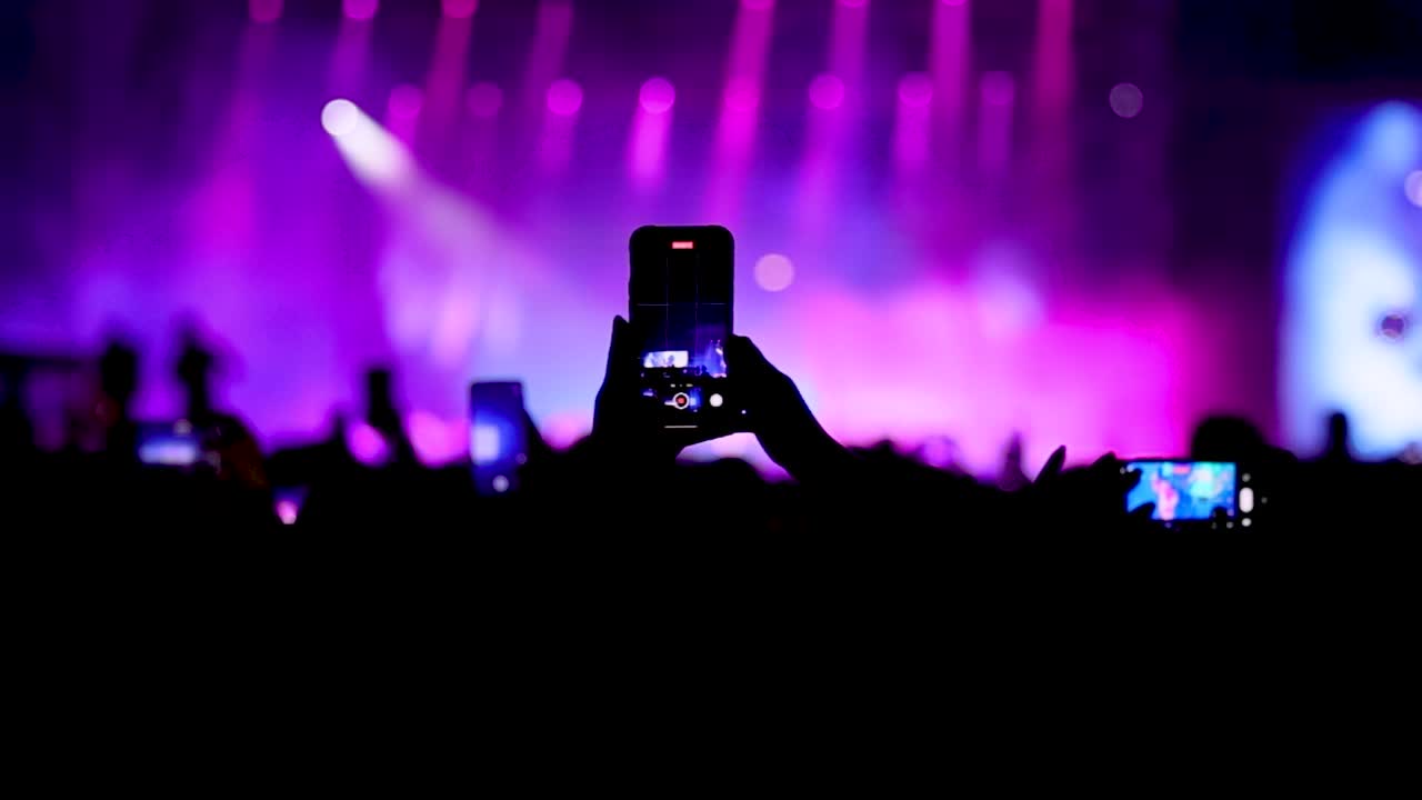 Fan che registrano video di un concerto dal vivo sul palco con i loro smartphone