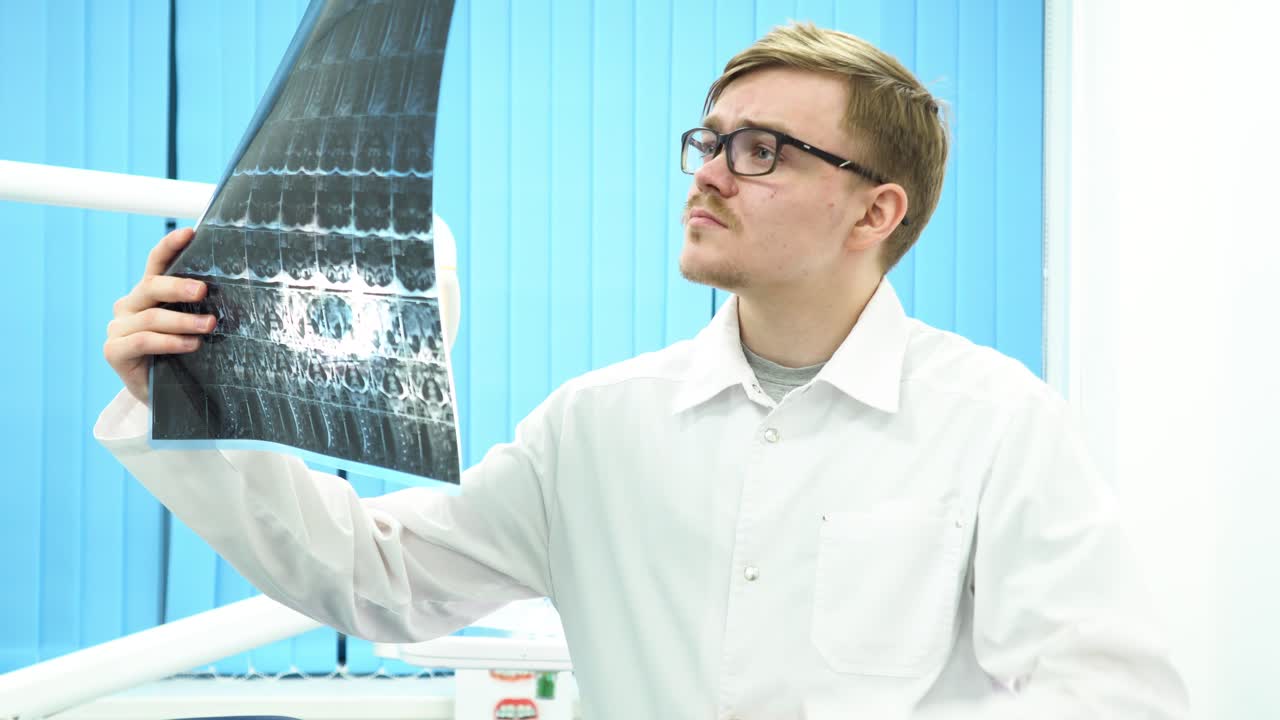 стоматолог рассматривает рентгеновские снимки.