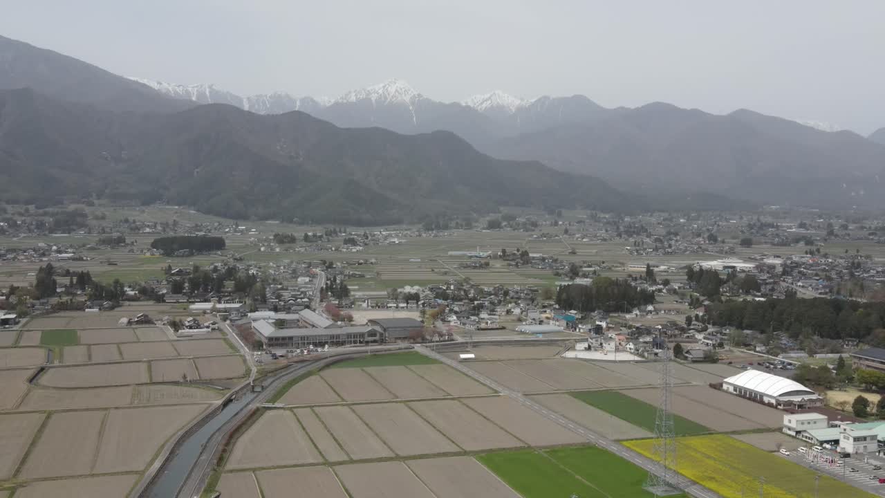 Aerial View Of Agricultural Farming Fields In Azumino Countryside With View Of Kamikochi National Park In Background. Dolly Back Shot