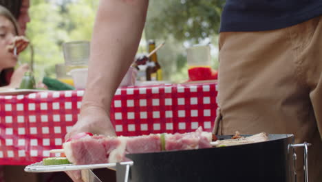 close-up of an unrecognizable man cooking meat in grill using metal tongues