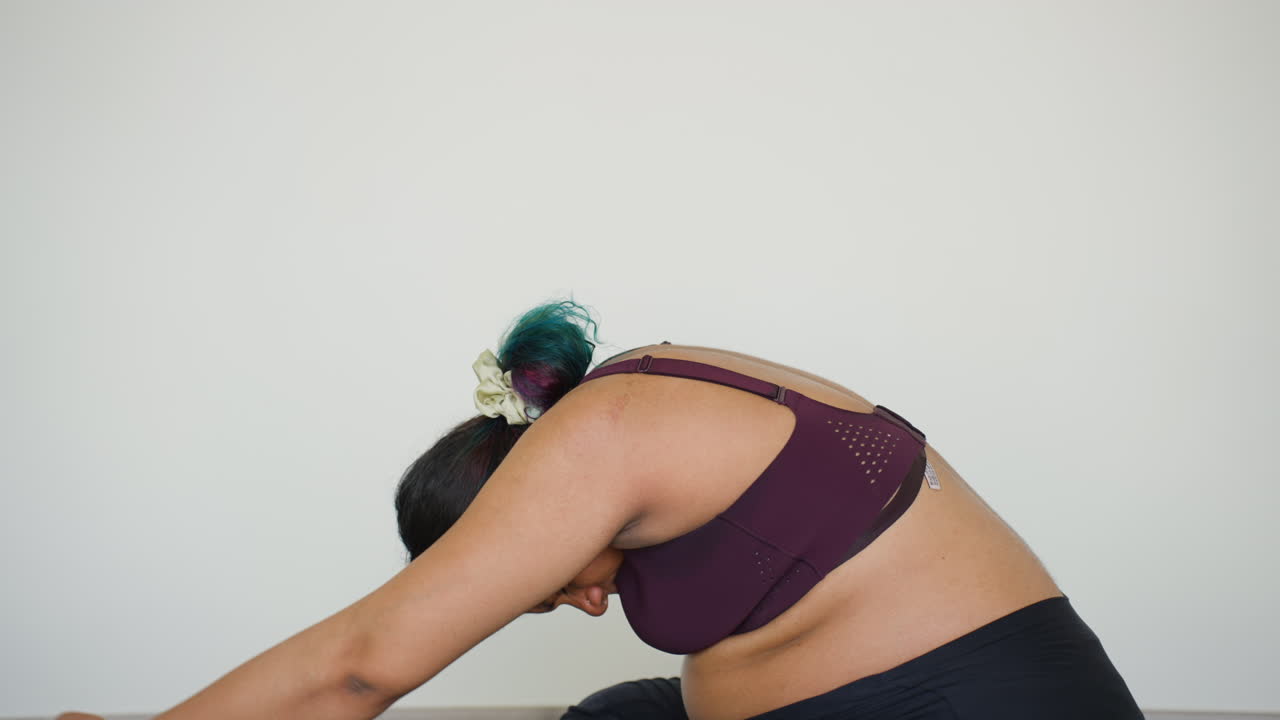 Jovem indiana no terceiro trimestre de gravidez sentada fazendo alongamento em pose de yoga após exercícios de treino