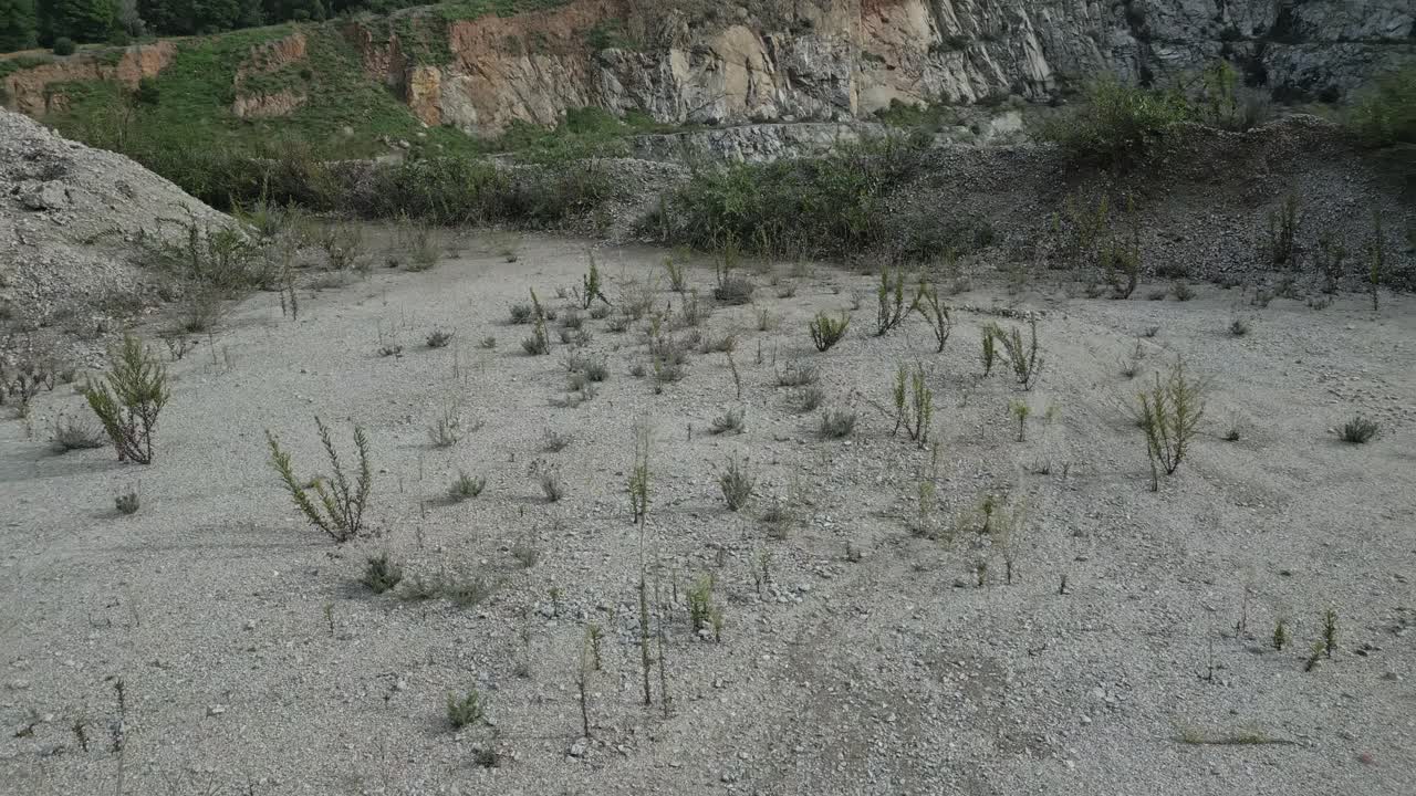 Gradual water accumulation transforming barren quarry into verdant pool, revealing natural landscape evolution through aerial perspective of rocky terrain