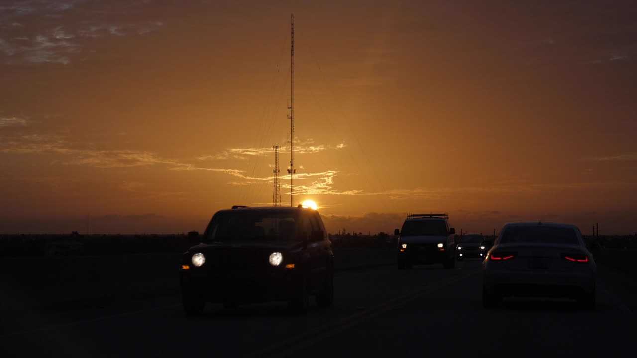 Slow motion shot of car silhouettes driving though with the sunrise coming over US-1 while driving north from Key West through the Florida Keys.