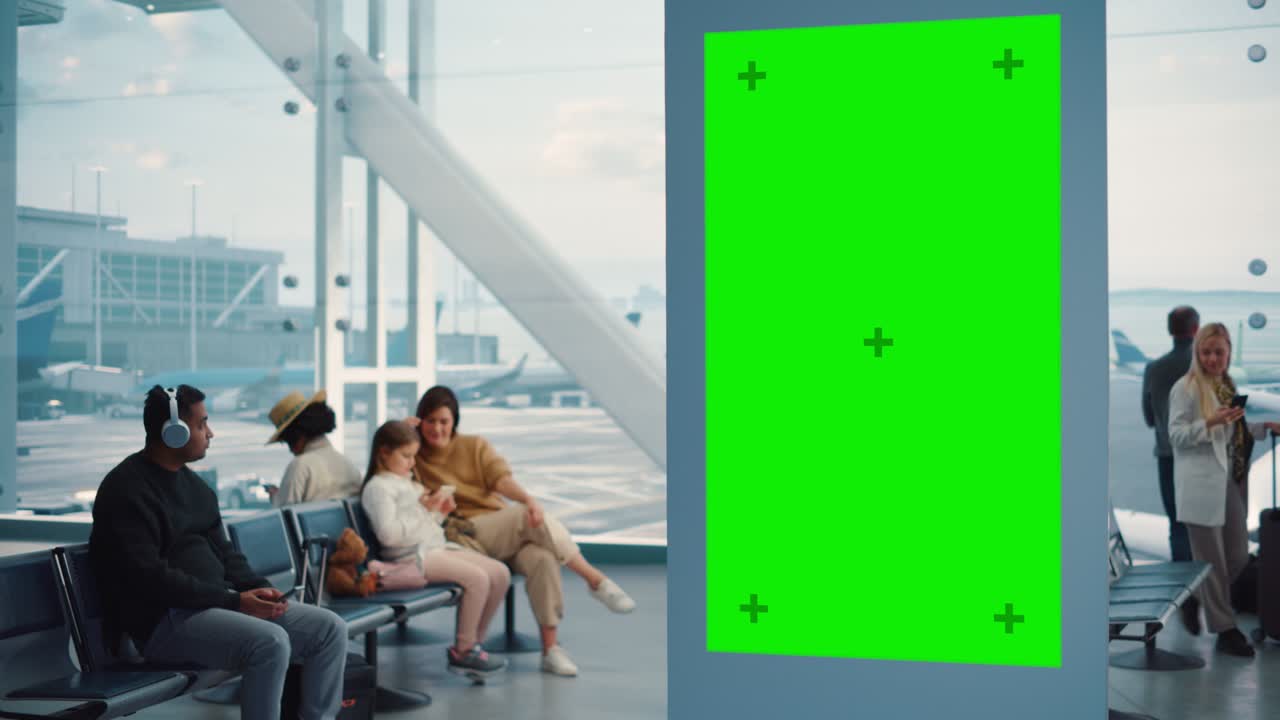 터미널: 녹색 화면 광고 표지판, 크로마 키와 함께 도착 디스플레이, 모형 광고 공간, 배경: 항공사 허브의 탑승 라운지에서 다양한 사람들이 비행기를 기다리고 있습니다.