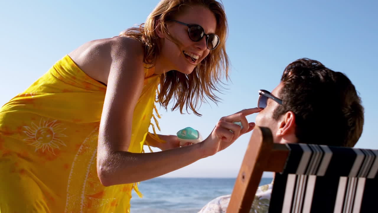 Woman applying sunscreen on the nose of a man