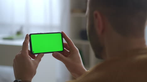 El-Hombre-Está-Viendo-La-Pantalla-Verde-De-Un-Teléfono-Móvil-Sosteniendo-Un-Moderno-Dispositivo-Horizontal-Y-Una-Aplicación-Para-Educación,-Comunicación-Y-Entretenimiento.