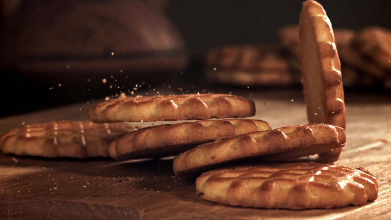 Golden Cookies Falling and Stacking on a Wooden Board in Slow Motion