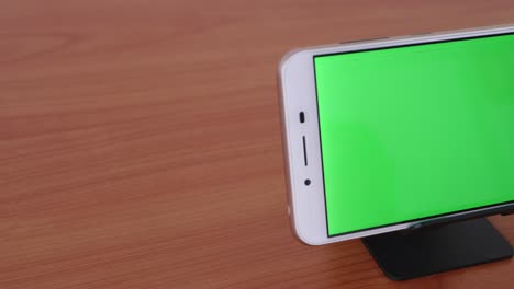 slide motion of the green screen phone is placed on a pedestal on a wooden table