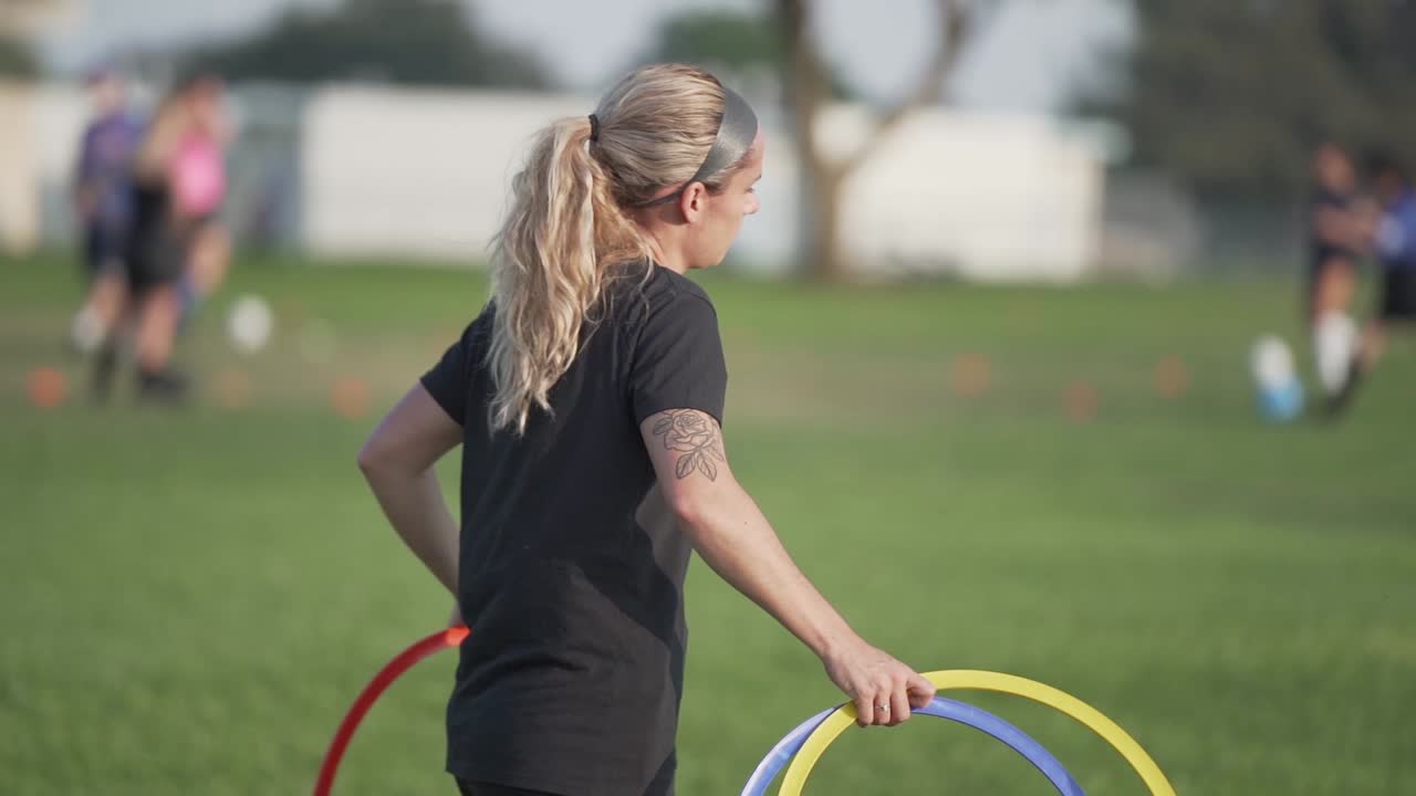 entrenador de fútbol femenino con anillos de entrenamiento de colores