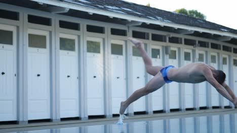 attractive male swimmer stands at the edge of the pool and jumps into the water