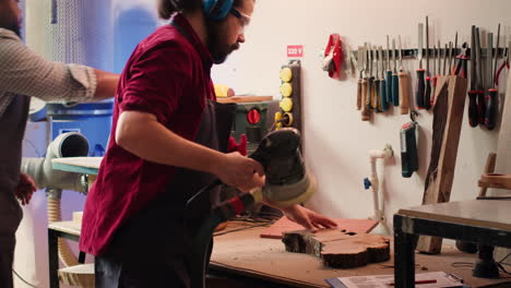 artisan with protecting equipment uses angle grinder on wood