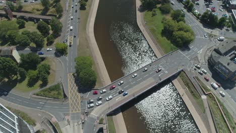 top down of a busy multi lane traffic junction or lights controlled roundabout over a shimmering river