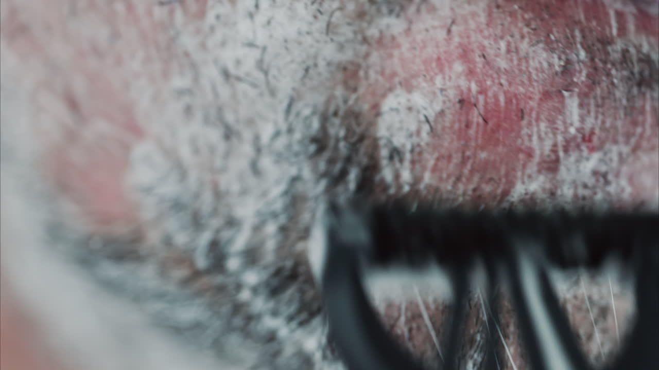 Close up of a man shaving his beard with a razor
