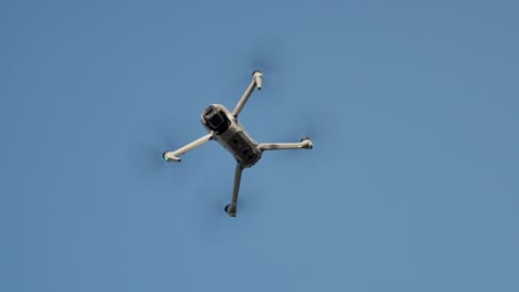 A large DJI drone flies smoothly against a clear blue sky on a calm day