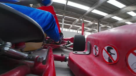 POV-wide-low-angle-shot-of-red-Gokart-driving-fast,-view-of-leg's-driver
