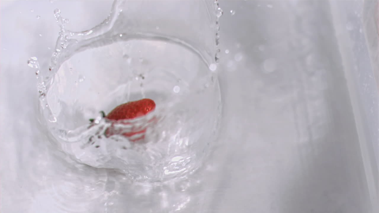 Strawberry falling into water in super slow motion