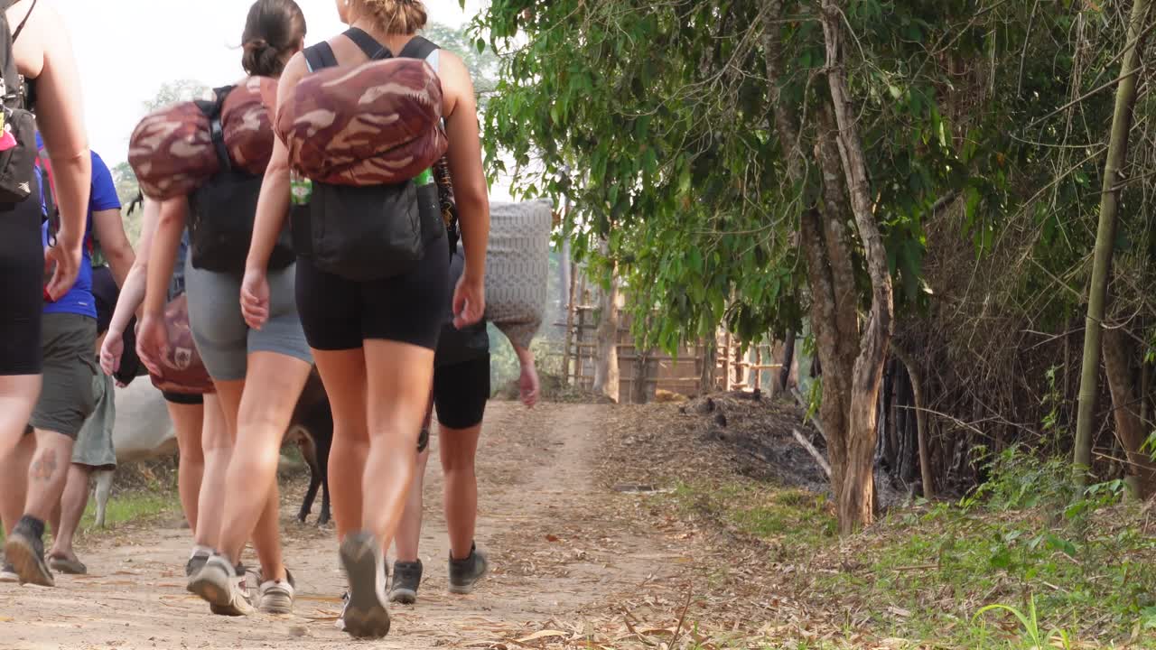 un grupo de mochileros jóvenes y aventureros está caminando y caminando hacia un pequeño pueblo con vacas al final del camino, en el norte de tailandia en el área de umpang