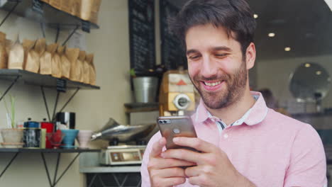 joven en la cafetería mirando el teléfono móvil