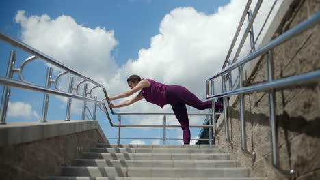 mujer estirándose en las escaleras al aire libre