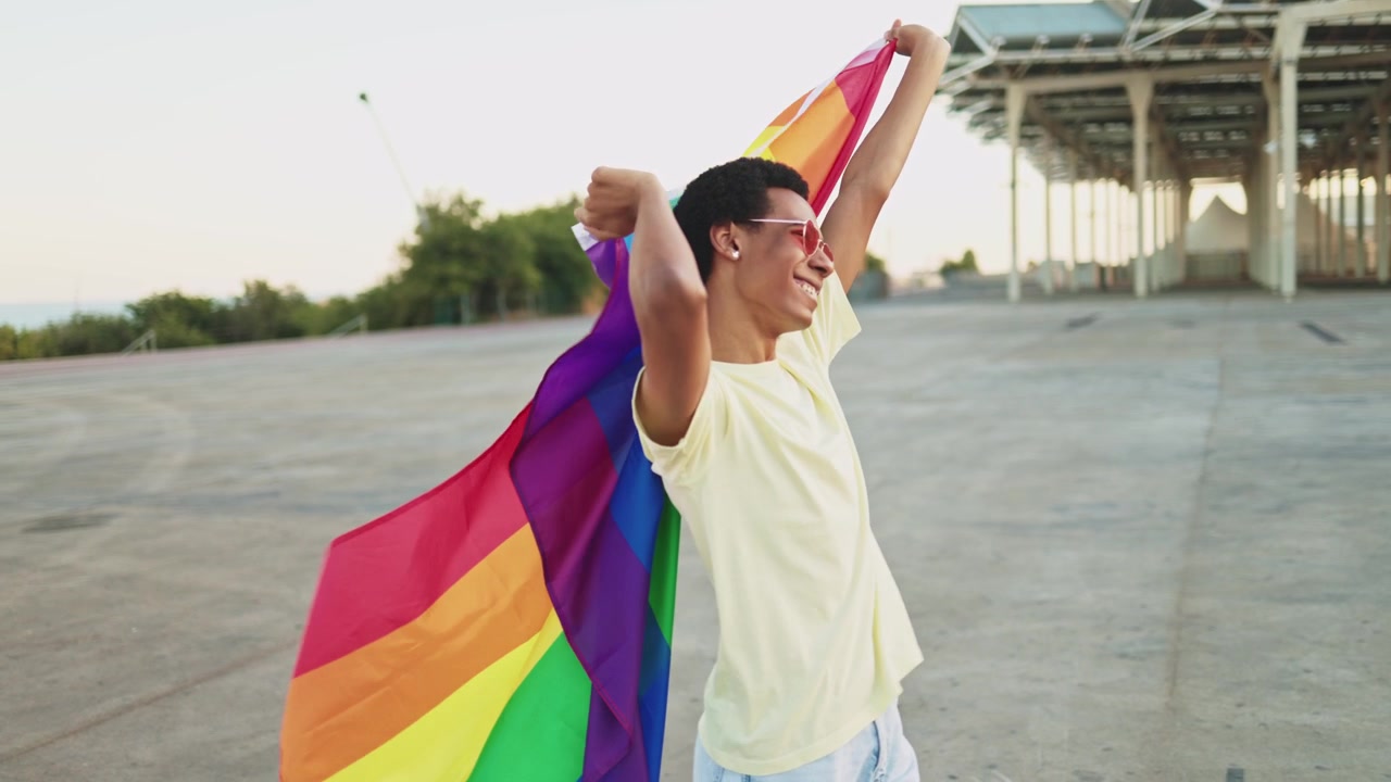 Happy Young Person Holding Rainbow Flag Outdoors