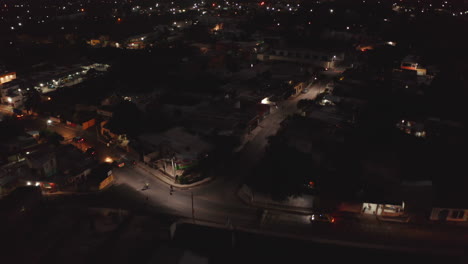 Forwards-fly-above-urban-neighbourhood-at-night.-Cars-driving-in-narrow-streets.-Valladolid,-Mexico