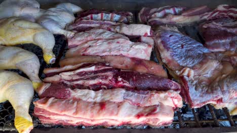 pollo crudo y carne de res cocinando lentamente en un asado tradicional, argentina