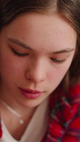 young woman wearing red checkered shirt looks down sitting in living room closeup slow motion. concentrated lady at work. pretty brunette woman at home