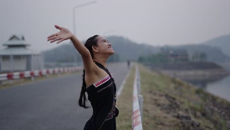 joyful woman with arms outstretched on a lakeside road