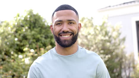 Retrato-De-Un-Feliz-Hombre-Afroamericano-Sonriendo-En-Un-Jardín-Soleado,-Cámara-Lenta