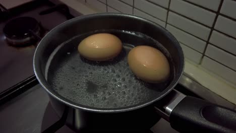 boiling two eggs in a saucer pan on a stove