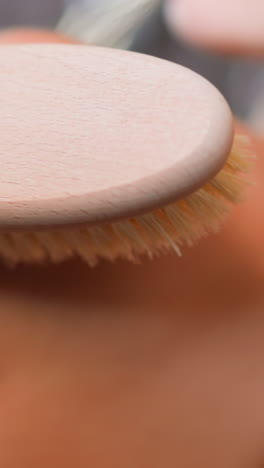 young woman makes gentle massage moving anti-cellulite brush along arm and shoulder in shower at home skincare routine slow motion extreme closeup