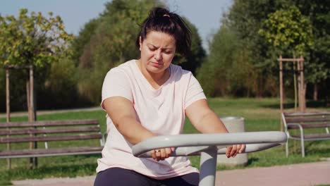 tired woman using exercise bike in public park