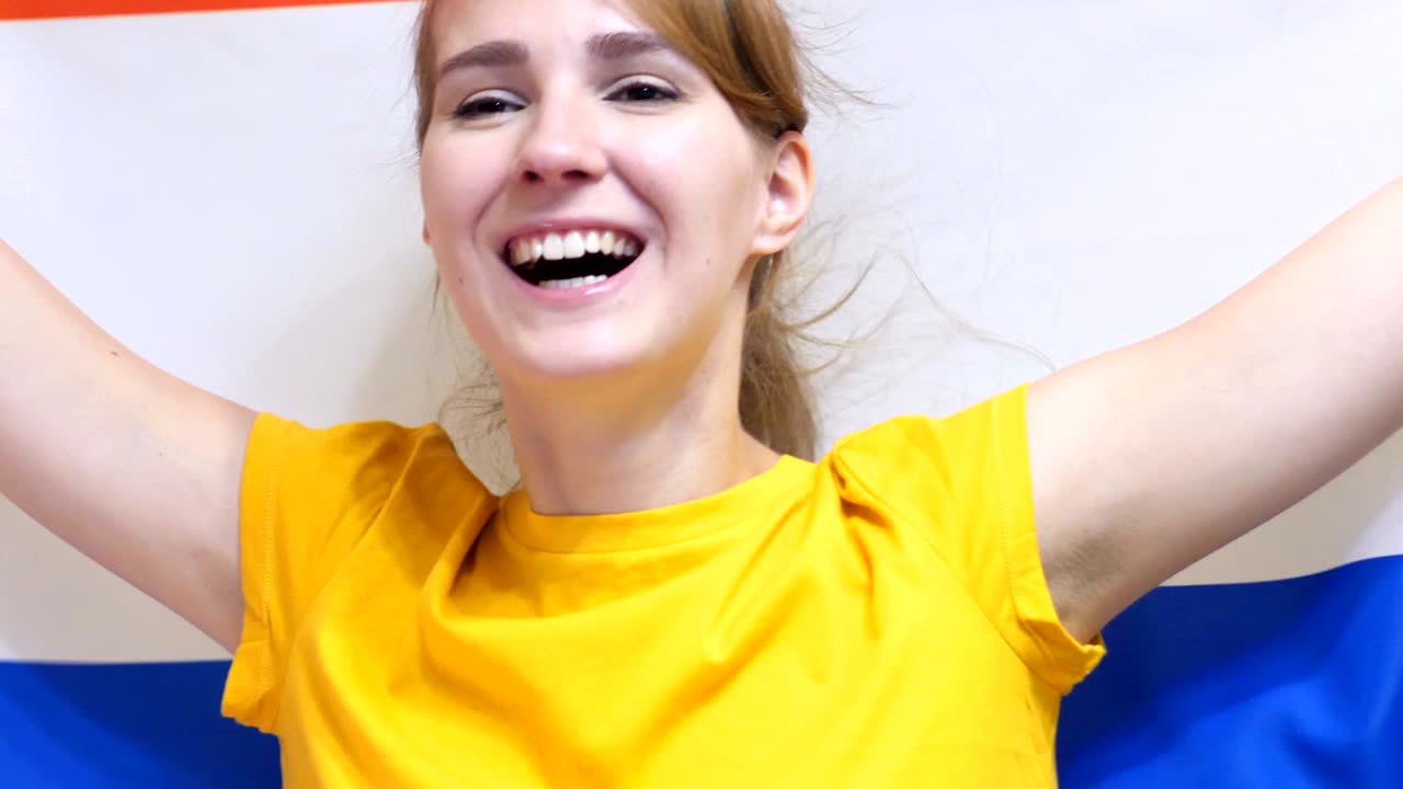mujer joven celebrando mientras sostiene la bandera de los países bajos en cámara lenta