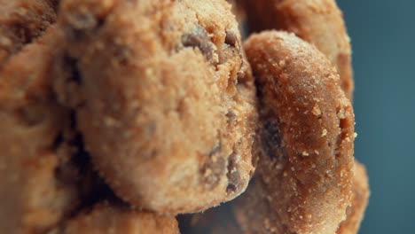 a vertical macro close up shot of a plate full of crispy chocolate chip cookies, on a 360 rotating stand, studio lighting, super slow motion, 120 fps, full hd video