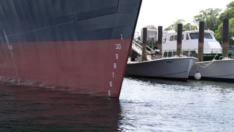 números alineados a lo largo de la proa de un barco grande atracado delante de buques marinos más pequeños