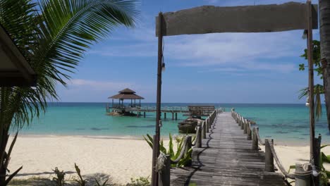 cartel vacío en una hermosa playa con un muelle que conduce a una casa en una isla tropical en el océano