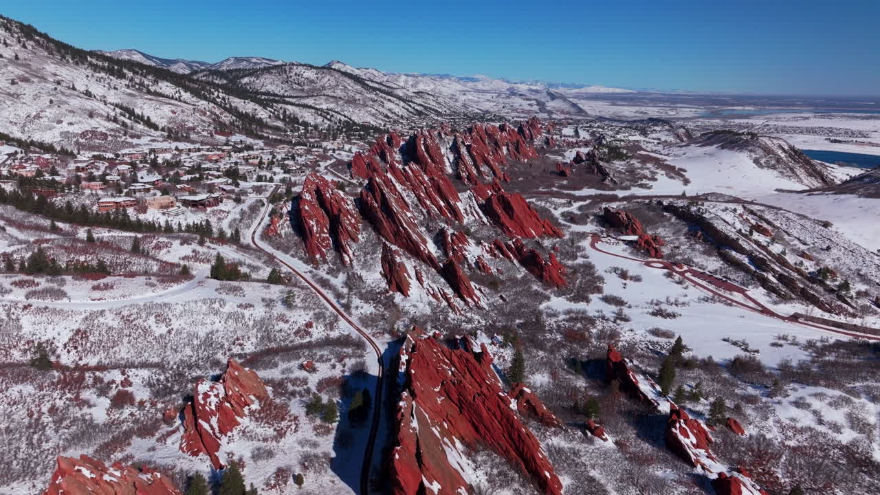 March winter morning snow stunning Roxborough State Park Littleton Colorado aerial drone over sharp jagged dramatic red rock formations Denver foothills front range landscape blue sky backwards motion