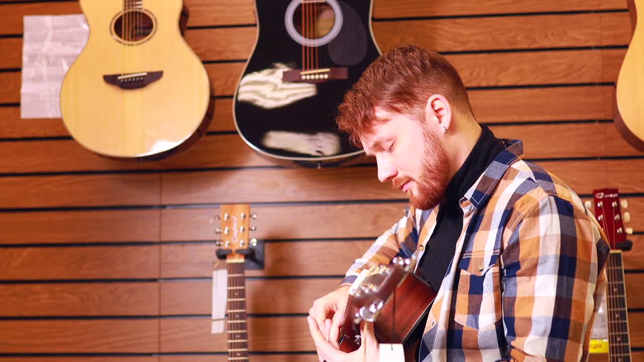 el hombre pelirrojo está eligiendo una guitarra acústica de calidad en la tienda de guitarras.