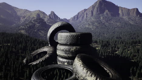mountainous landscape features stacked tires amidst pine trees and rocky peaks