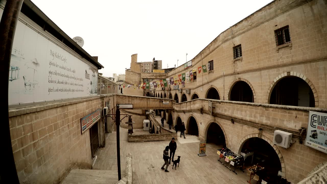 Calles empedradas en el lugar de un antiguo canal, escaleras de forma pintoresca, gente caminando, niño con perro, Sanliurfa