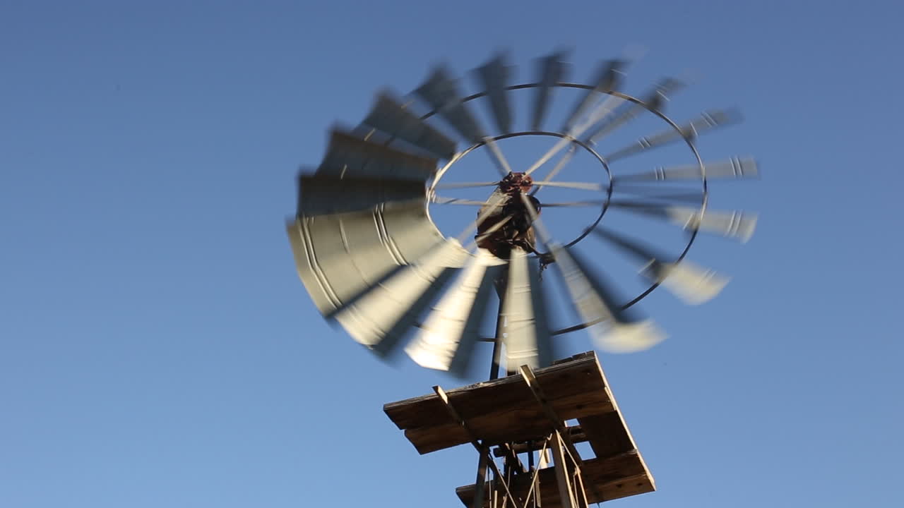 활기차고 맑은 푸른 하늘을 배경으로 회전하는 농업용 풍력 펌프의 낮은 각도