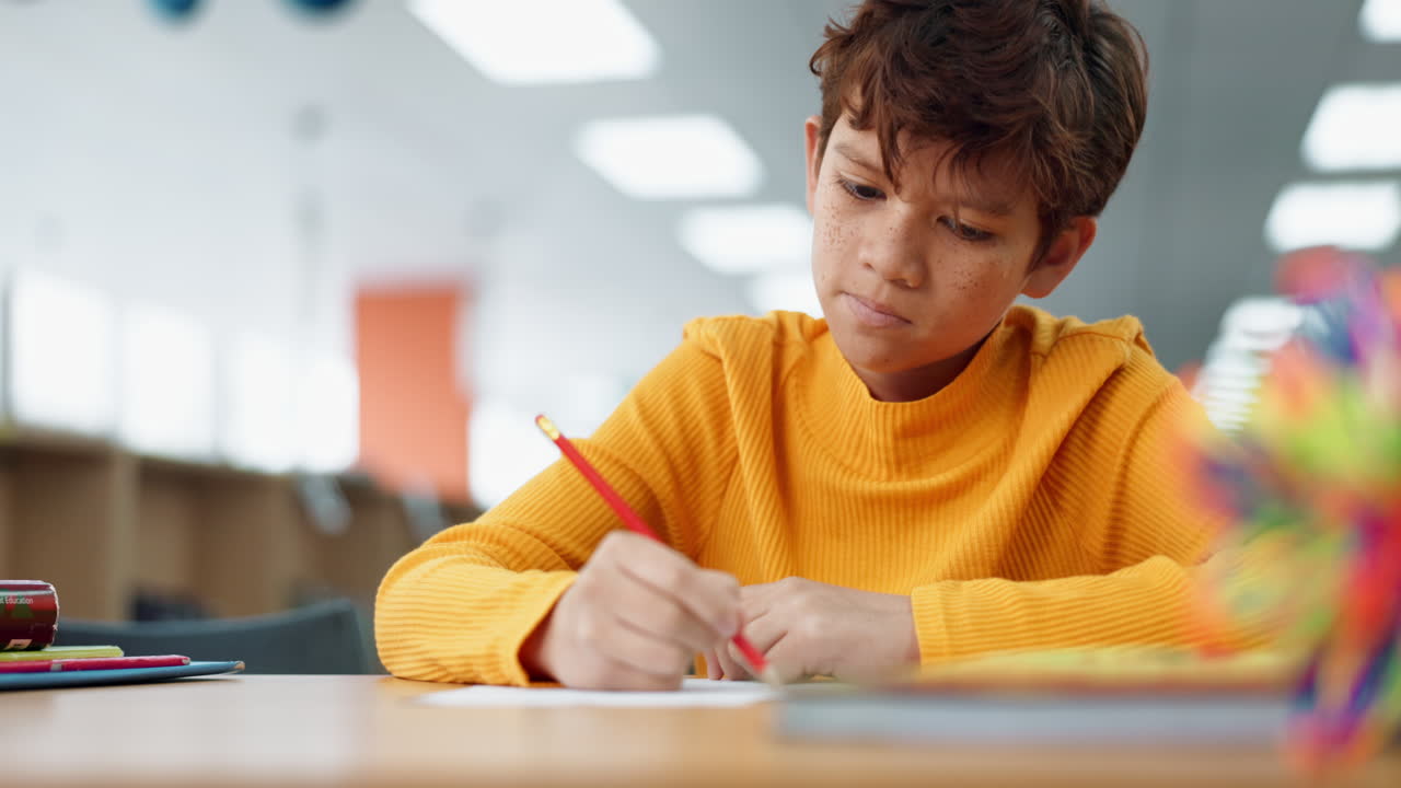 Boy writing at a desk in a classroom