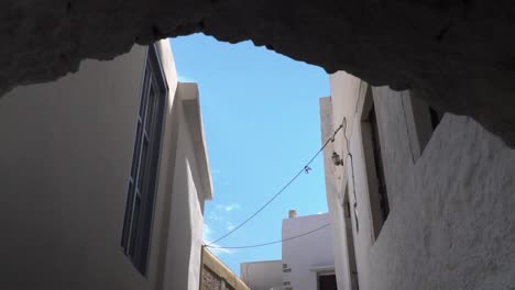 reveal of typical white greek houses and sky behind arch slow motion